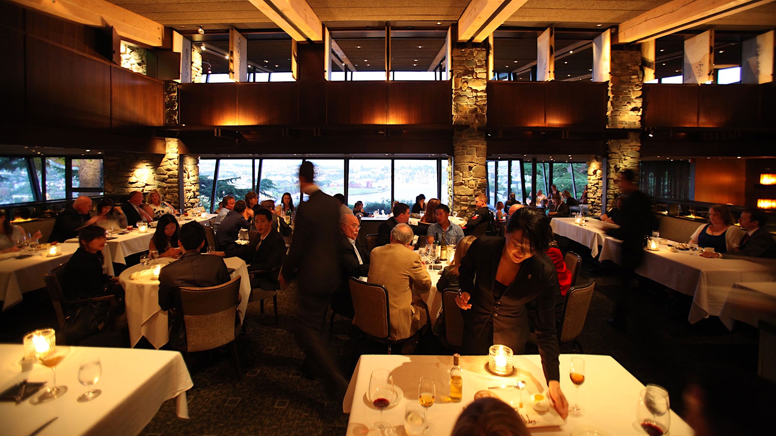 People in the modern-design dining room of Canlis, with wood and stone accents and large windows
